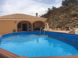 une grande piscine bleue en face d'une maison dans l'établissement Casa Cuatro Vientos - Barranco Del Sol, à Almogía