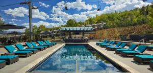 a pool with blue lounge chairs and a swimming pool at Viceroy Snowmass in Snowmass Village