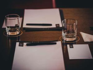 a wooden table with two glasses and a pen on it at La Griffe Hotel Roma in Rome