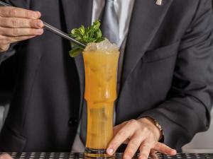a man in a suit is stirring a drink at La Griffe Hotel Roma in Rome