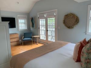 ein Schlafzimmer mit einem weißen Bett und einem blauen Stuhl in der Unterkunft The Bungalow in Nantucket