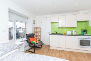 a kitchen with white cabinets and a chair in a room at Bristol City Budget Studio Stay in Bristol