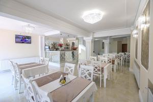 a restaurant with white tables and chairs and a counter at Pensiune Restaurant Select in Băile Herculane