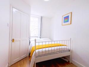 a white bedroom with a bed with a yellow blanket at Orchid 2 At Regent's Park in London