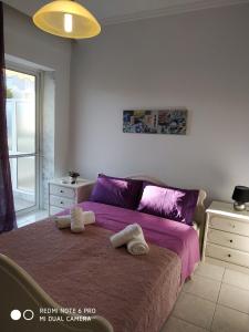 Un dormitorio con una cama morada con toallas. en Cosi Apartment, en Paralia Dionisiou
