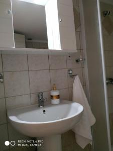 lavabo blanco en el baño con espejo en Cosi Apartment en Paralia Dionysiou