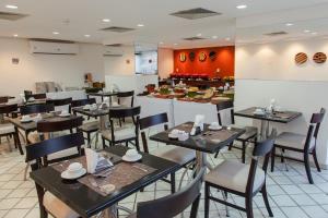 a restaurant with tables and chairs and a counter at Mercure Recife Navegantes in Recife