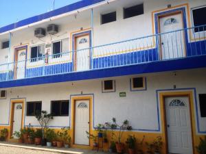 a white building with a blue and white balcony at Hotel Sarabi in Barra de Navidad