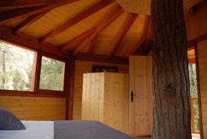 a bedroom in a wooden cabin with a tree at Cabanes Dosrius in Canyamás