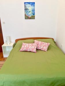 a green bed with two pink pillows on it at Sobe Bosiljka in Nin