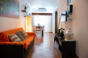 sala de estar con sofá naranja y TV en Casa da Sereia, en Sesimbra