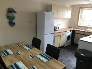 uma cozinha com uma mesa com cadeiras e um frigorífico em Heb Holiday, Self Catering Accommodation, Isle of Benbecula em Gramisdale