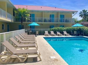 a resort pool with lounge chairs and umbrellas at Dunes Inn & Suites - Tybee Island in Tybee Island