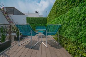 two chairs sitting on a deck next to a hedge at JUUB New Beautiful Suite Nuevo Polanco (R2) in Mexico City