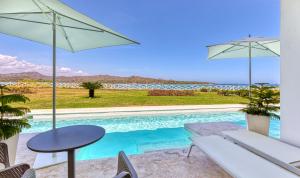 a villa with a swimming pool with a table and umbrellas at Senator Puerto Plata in San Felipe de Puerto Plata