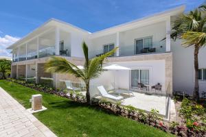 a large white house with chairs and an umbrella at Senator Puerto Plata in San Felipe de Puerto Plata
