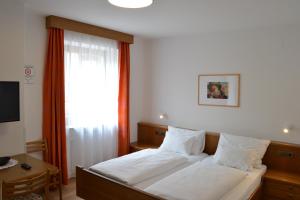 コッレピエトラにあるGasthof Pizzeria Unterwirtのベッドルーム1室(白いシーツ付きのベッド1台、窓付)