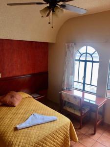 a bedroom with a bed and a table and a ceiling fan at Hotel Virreynal in Córdoba