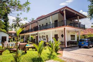 a house with a balcony and a car parked in the yard at Haus Berlin in Bentota