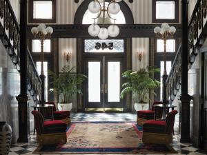 a hallway with two chairs and a door with windows at Maison de la Luz in New Orleans