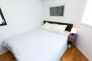 a bedroom with a white bed and a night stand at Sangen-jaya House-O in Tokyo