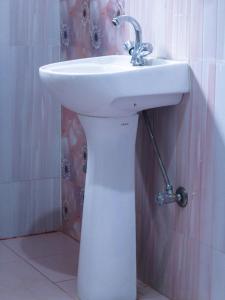 lavabo blanco en el baño junto a una ducha en Bardia Jungle Cottage, en Bardiyā