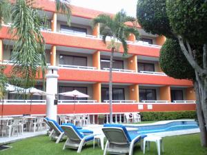 a resort with chairs and a pool and a building at Hotel Real del Sol in Cuernavaca