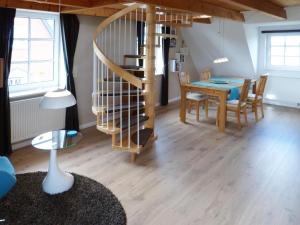 a living room with a table and a spiral staircase at Haus Nordlicht Ferienwohnung *Bi a Maln* in Nebel