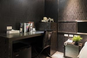 escritorio con silla en una habitación con azulejos negros en Vendome East Inn en Taipéi