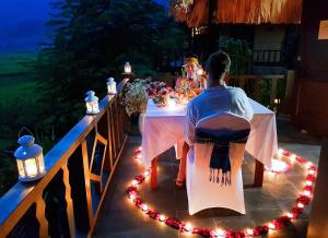 a man and woman sitting at a table with lights at Mai Chau Ecolodge in Mai Châu