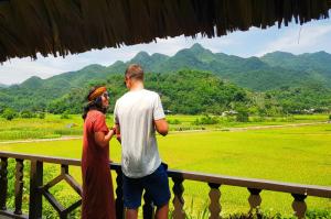 a man and woman standing on a porch looking at a field at Mai Chau Ecolodge in Mai Châu