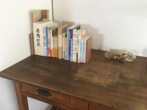kilka książek siedzących na drewnianym stole w obiekcie SOCKET w mieście Minami Aso