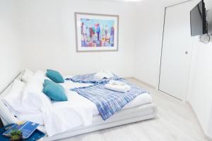białe łóżko z niebieskimi poduszkami w białym pokoju w obiekcie MiKlod Apartments w mieście Palermo