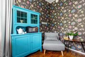 un armario azul y una silla en una habitación con papel pintado floral en Villa Aia Studio, en Pärnu