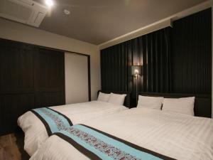 a bedroom with two beds with white sheets at BIG ROOM GUEST HOUSE in Osaka