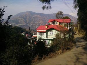 una casa con techo rojo al lado de una carretera en AMBIKA HOME STAY en Solan