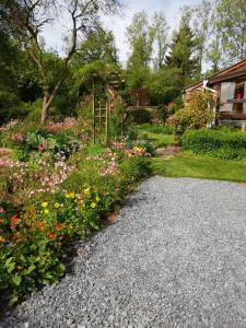 un jardín con flores y una entrada de grava en Aux doux rêves, en Provèdroux