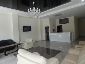 una sala de estar con muebles blancos y una lámpara de araña. en Hotel Belugo en Batumi