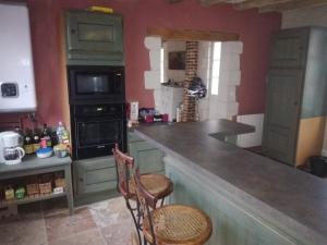 a kitchen with green cabinets and a counter with two chairs at Chambre d'hôte Monthodon in Monthodon