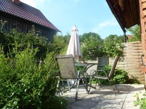 um pátio com uma mesa, cadeiras e um guarda-sol em Ferienwohnung Lotti em Brotterode