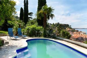 einen Pool mit 2 Stühlen und Blick auf das Wasser in der Unterkunft Mediterranean Villa with an Amazing View and a Pool by Loft in Piran