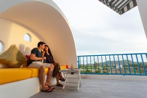 a couple sitting on a couch in a room with a view at Costa Village Bangsaray in Bang Sare