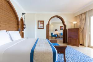 a hotel room with a large bed and a chair at Kempinski Hotel Soma Bay in Hurghada