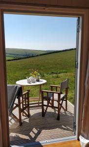 a table and chairs on a deck with a view of a field at The Wheelhouse in Bude
