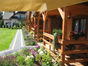 a wooden house with a porch and flowers at Domki w Ogrodzie in Stegna