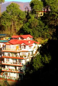 um grande edifício branco com telhados vermelhos numa montanha em AMBIKA HOME STAY em Solan