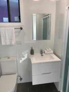 a bathroom with a toilet, sink, and mirror at Huskisson Beach Resort in Huskisson