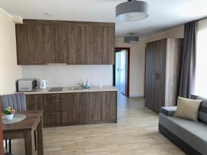 a kitchen with wooden cabinets and a living room at Willa Kormoran in Augustów