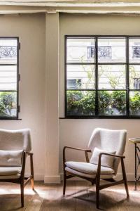 um quarto vazio com duas cadeiras e janelas em Hotel Verneuil Saint Germain em Paris