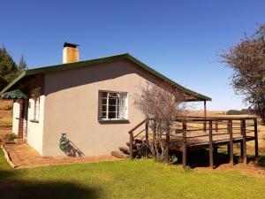 a small house with a porch and a window at Dabchick Cottage in Dullstroom